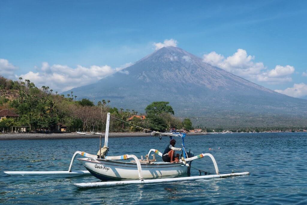 A fisherman on a traditional boat in Amed, with the Mont Agung behind